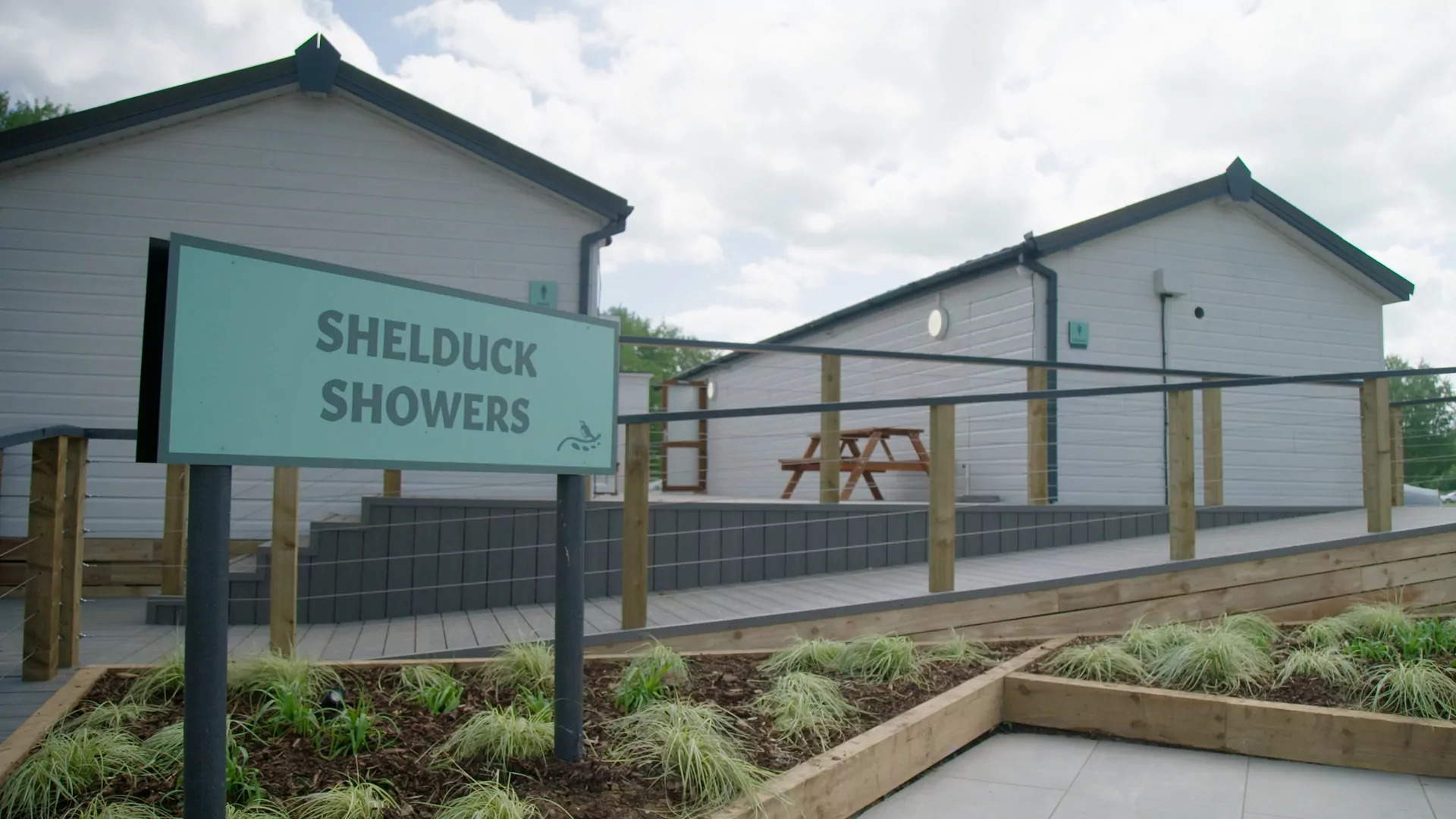 Exterior view of the Shelduck Showers building with modern facilities and outdoor seating area at Billing Aquadrome.