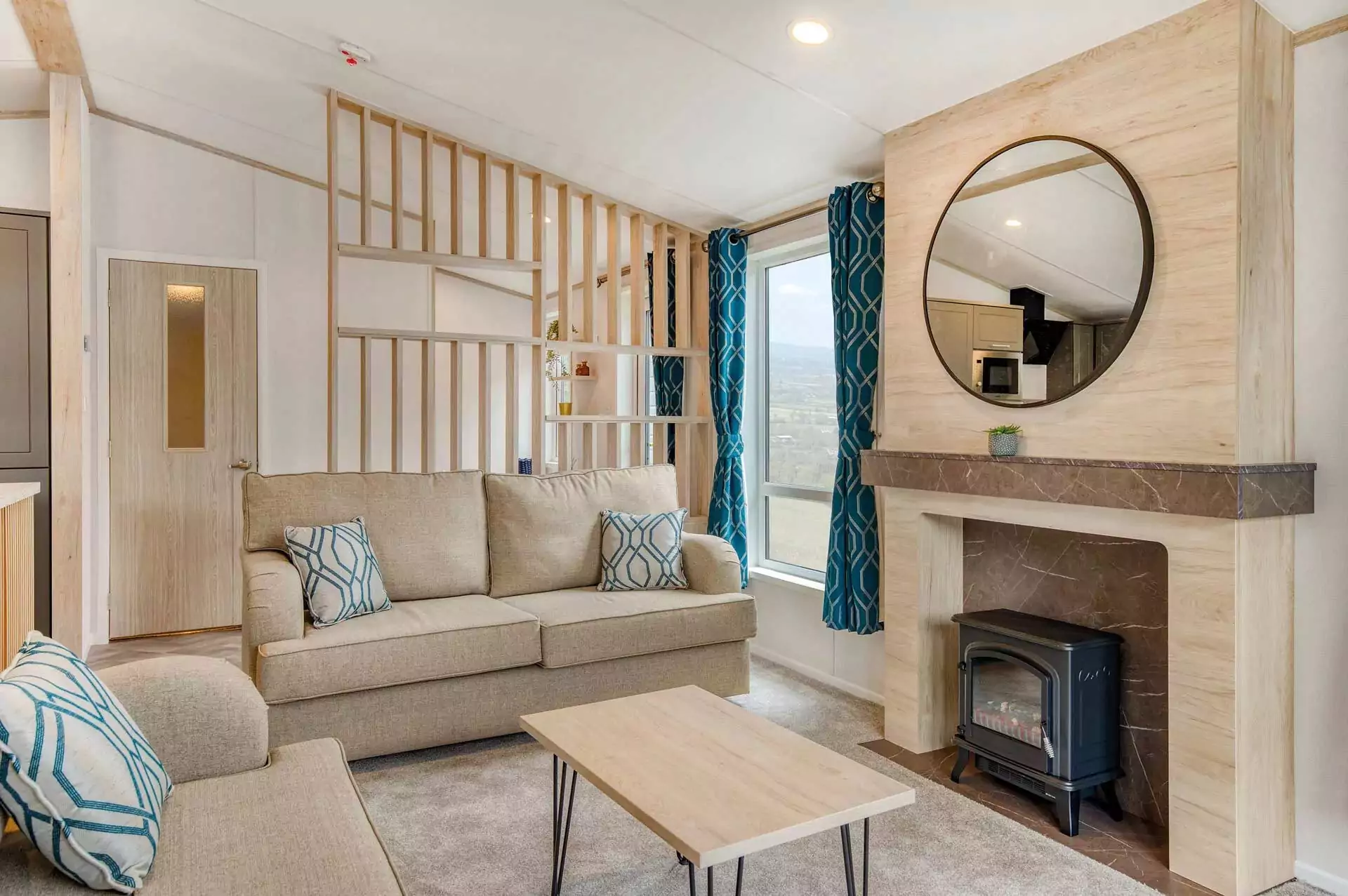 Modern lodge living room at Billing Aquadrome featuring a cosy fireplace, sofa, and bright blue curtains.