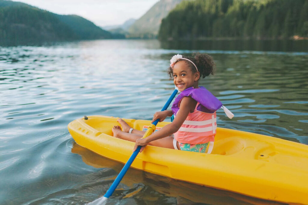Smiling child kayaking in a bright yellow boat on the lake at Billing Aquadrome