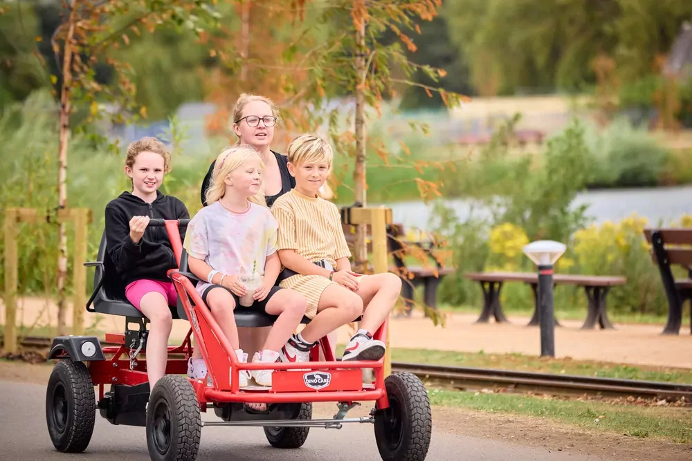 Group of children enjoying a ride together on a red pedal cart at Billing Aquadrome