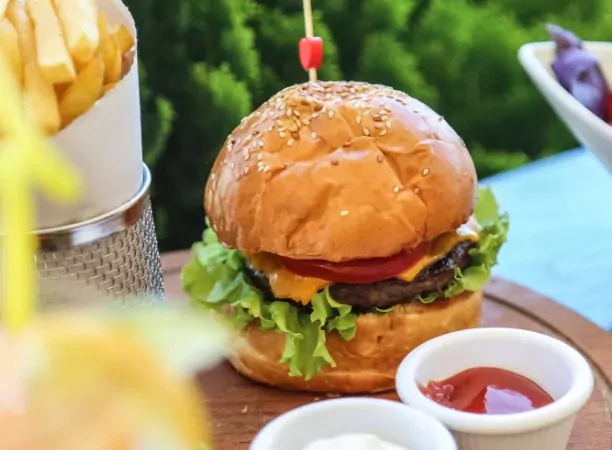 Close-up of a juicy cheeseburger with lettuce and tomato, served with golden chips and ketchup at Billing Aquadrome.