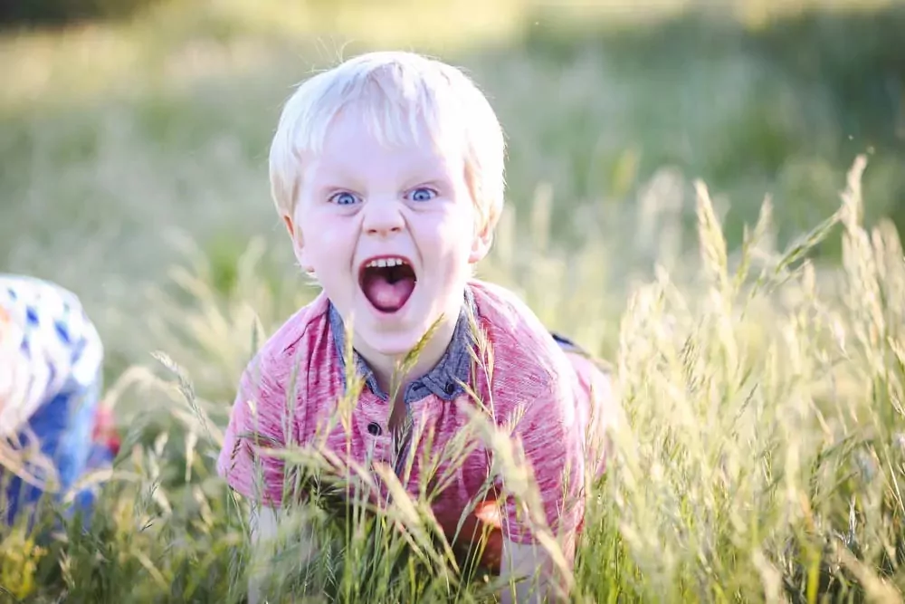 Excited young boy playing in tall grass and enjoying outdoor fun at Billing Aquadrome