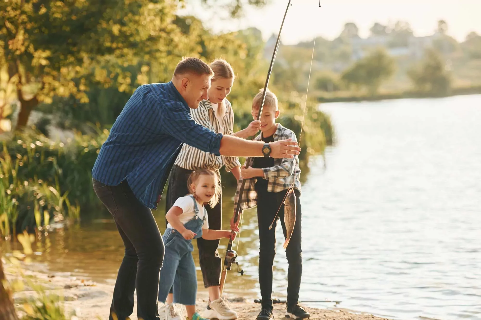 Family fishing together at the lakeside in Billing Aquadrome, with a child proudly holding a freshly caught fish
