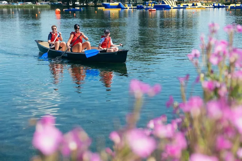 Three people wearing life jackets canoeing on the lake at Billing Aquadrome