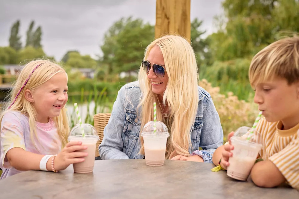 Mother and children enjoying milkshakes at an outdoor cafe by the lake at Billing Aquadrome