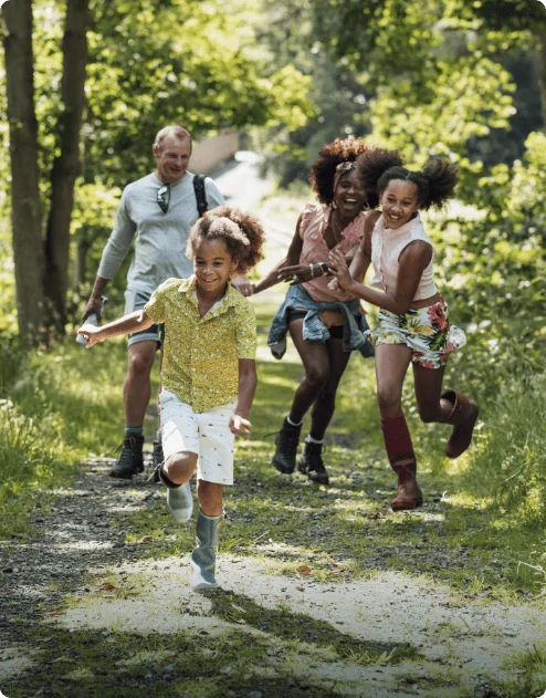 A family of 4 running on a pathway in the middle of a forest