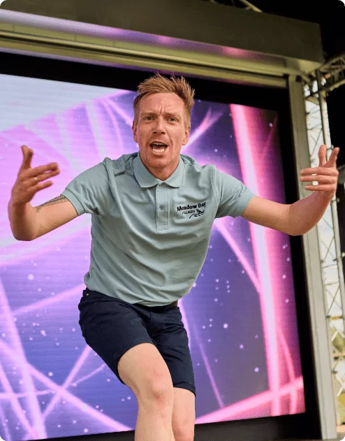 A man on stage at Meadow Bay Villages, showcasing his skills to an enthusiastic audience.