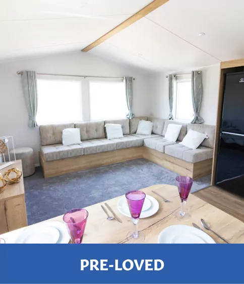 Interior of a pre-loved holiday home with L-shaped seating, dining area, and bright natural light.