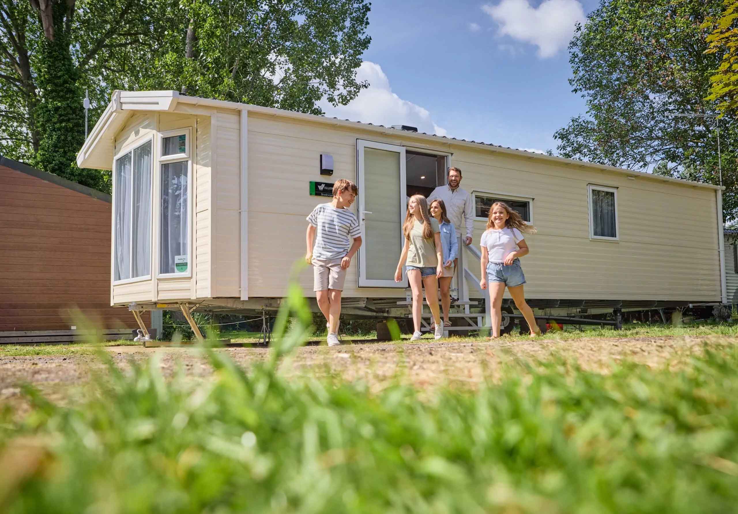 Family stepping out of a modern static caravan on a sunny day at Meadow Bay Villages Billing Aquadrome