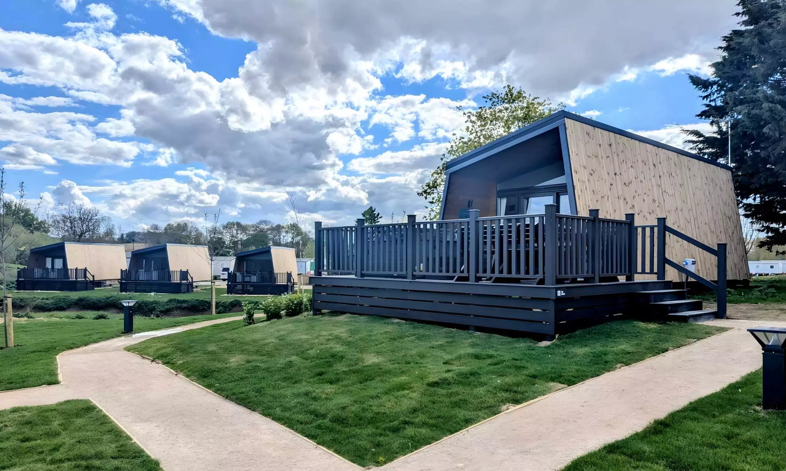 Contemporary glamping lodges with private decking and landscaped surroundings at Billing Aquadrome, part of Meadow Bay Villages.