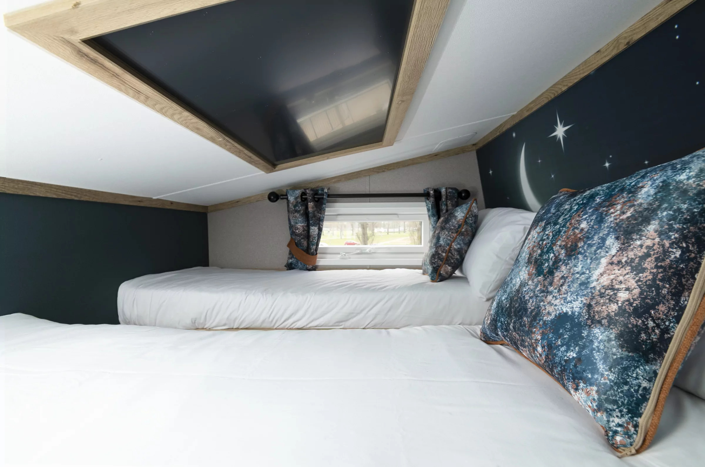 Cosy twin bed sleeping area with night sky-themed decor in a family holiday lodge at Billing Aquadrome, part of Meadow Bay Villages.