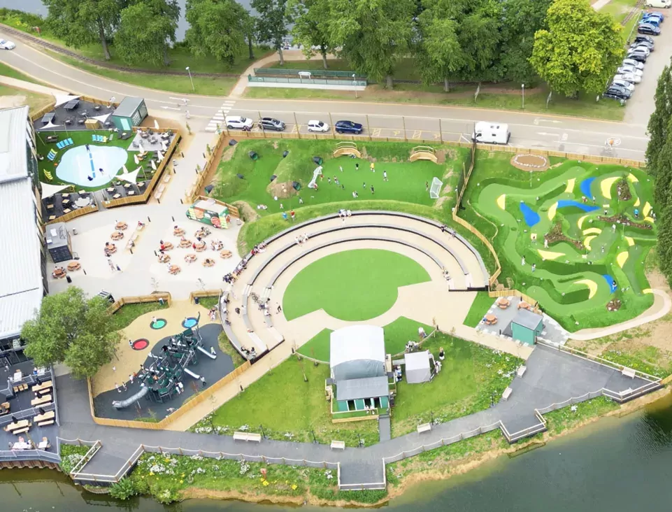 Aerial view of Billing Aquadrome’s activity zone featuring amphitheatre seating, mini-golf course, kids’ playground, splash zone, and lakeside paths