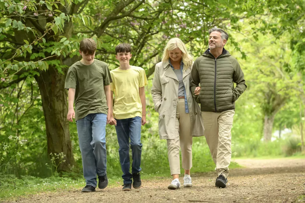 Family walking together along a leafy woodland path at Meadow Bay Villages Billing Aquadrome