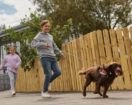 Children happily walking their dog along a wooden boardwalk near the entertainment complex at Billing Aquadrome, part of Meadow Bay Villages.