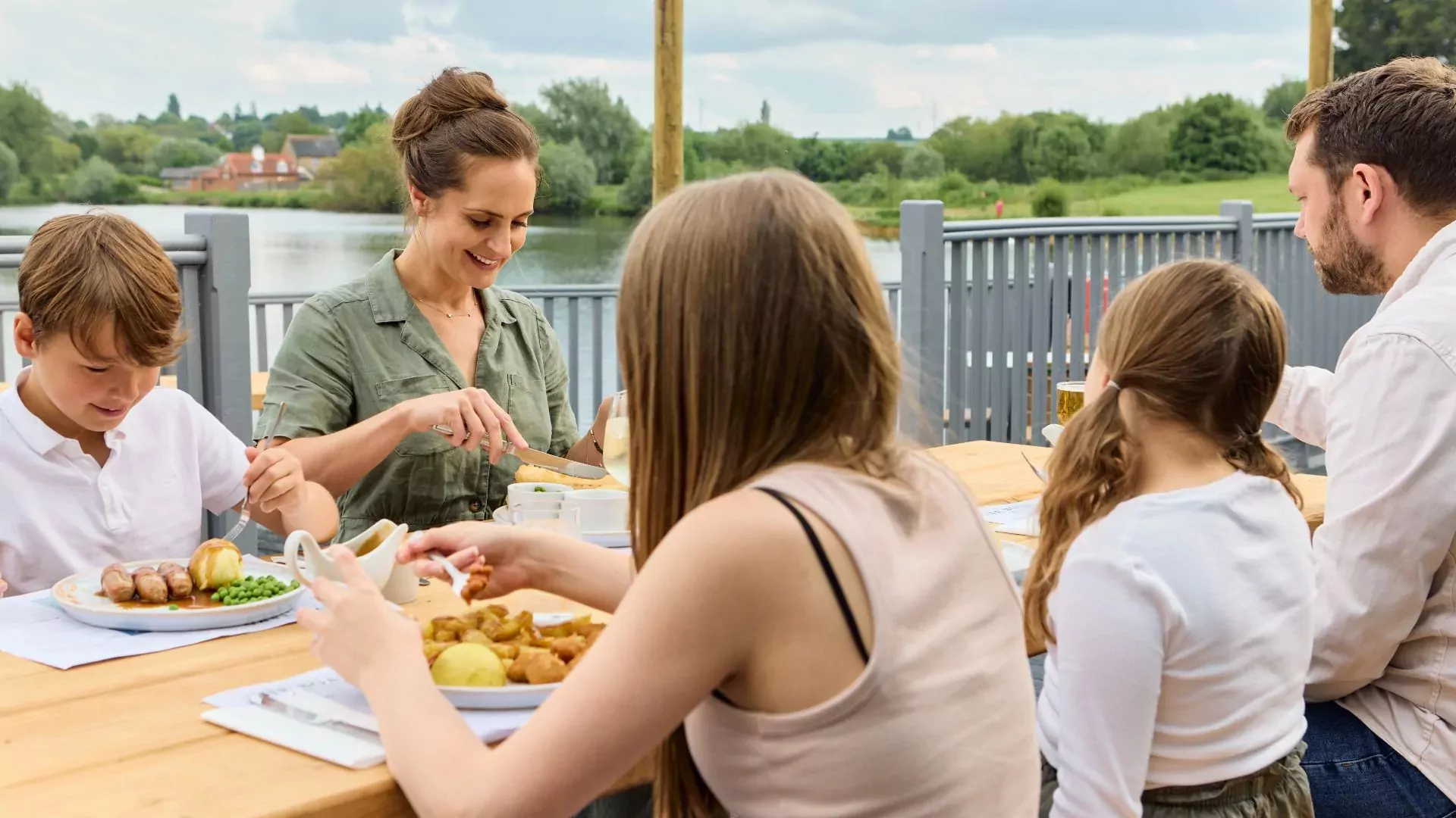 Family enjoying an outdoor meal together beside the lake at Meadow Bay Villages Billing Aquadrom