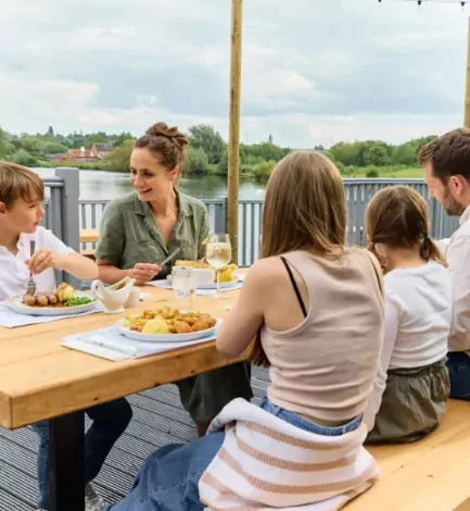 Family enjoying a relaxed outdoor meal together on the lakeside terrace at Billing Aquadrome holiday park