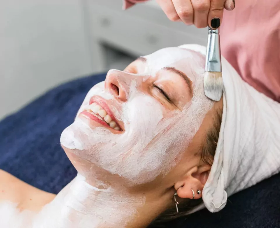 Woman smiling during a relaxing facial treatment at Serene Hair and Beauty Salon, Billing Aquadrome, part of Meadow Bay Villages.