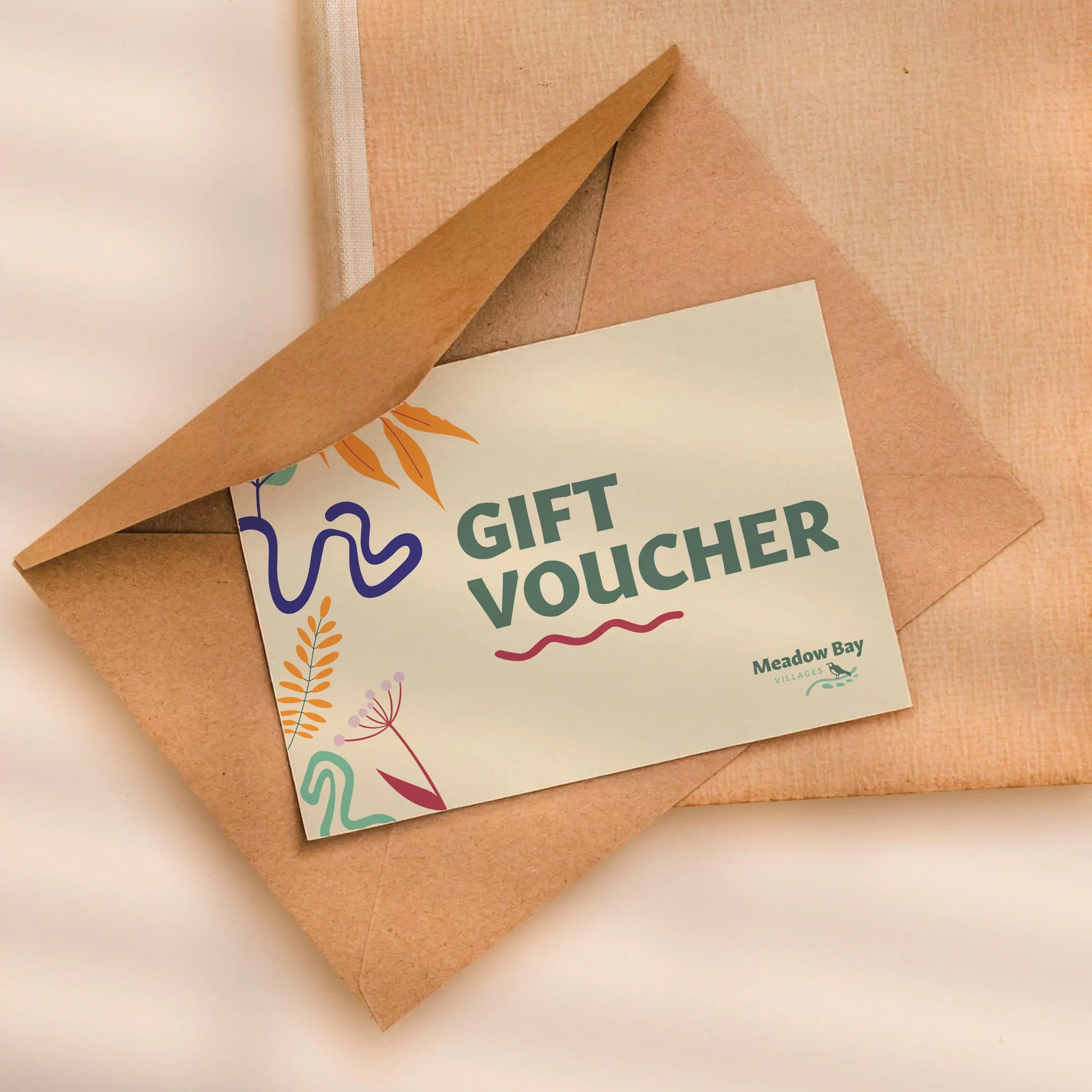Meadow Bay Villages gift voucher partially revealed in a brown envelope on a soft neutral background