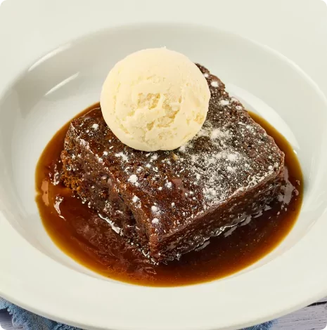 Delicious sticky toffee pudding topped with vanilla ice cream and drizzled in rich toffee sauce – a popular dessert option at Meadow Bay Villages restaurants.