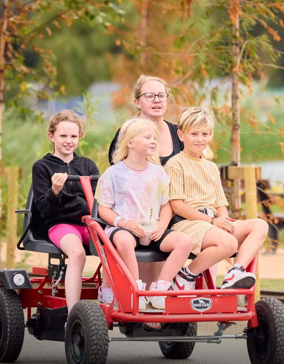 A group of children riding together on a fun red dino cart during outdoor activities at Billing Aquadrome.