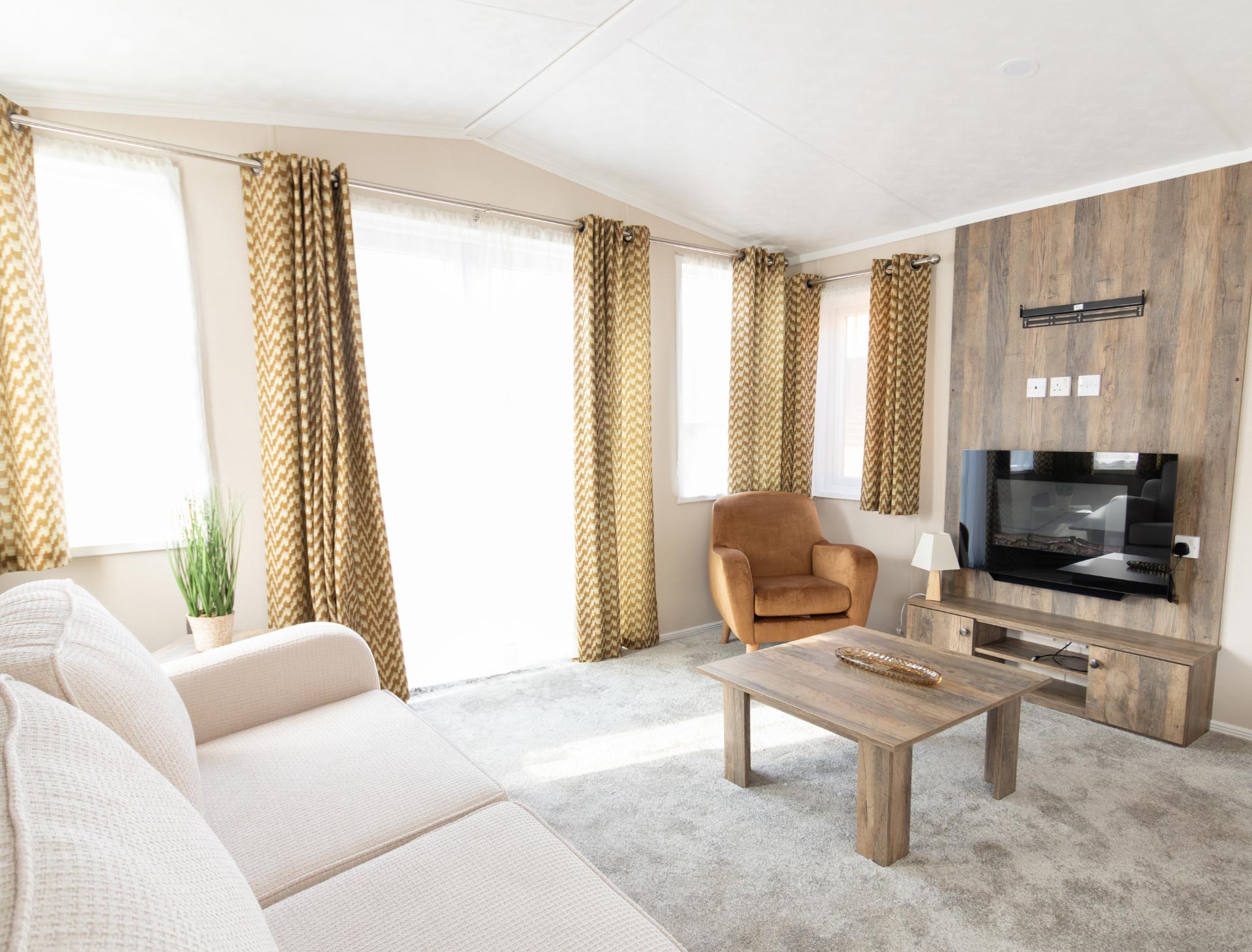 Bright and modern holiday home living room with sofa, armchair, and TV unit at Billing Aquadrome.