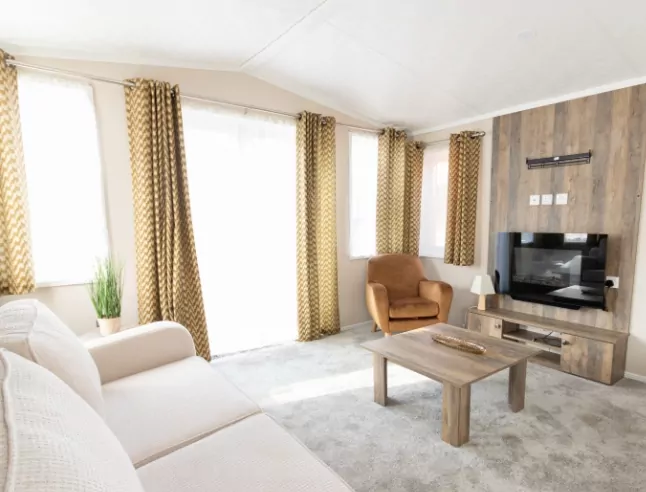 Bright and modern holiday home living room with sofa, armchair, and TV unit at Billing Aquadrome.