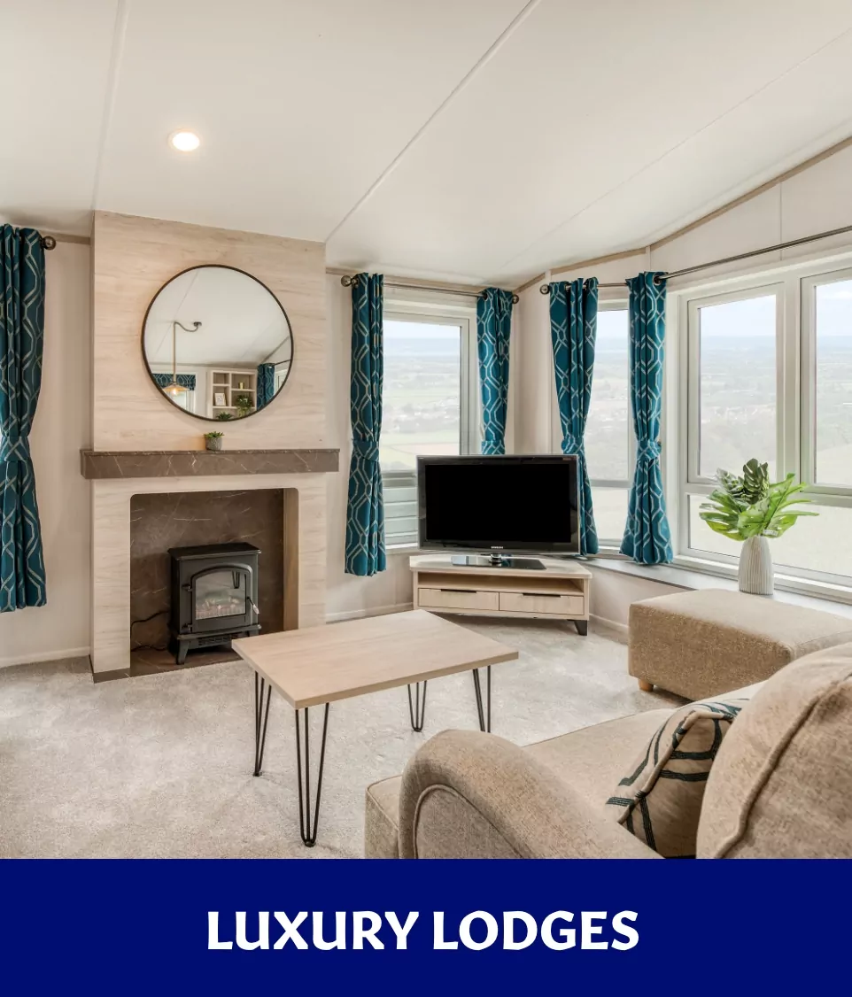 Spacious holiday lodge living room with fireplace, large windows, and TV at Billing Aquadrome.