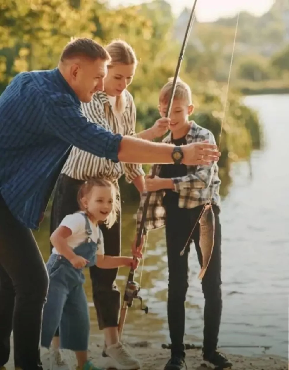 Family fishing together by the lakeside and catching a fish at Billing Aquadrome.