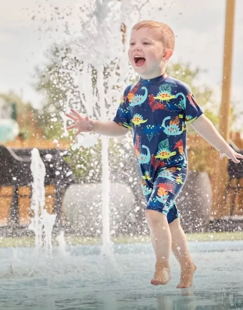 Young child running and laughing through water fountains at the splash park in Billing Aquadrome.