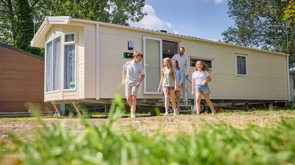 Family stepping out of their holiday caravan and enjoying time together outside their accommodation at Billing Aquadrome