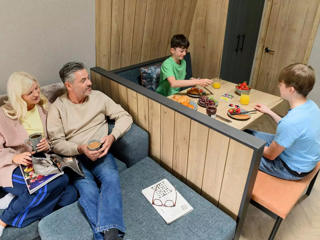 A family enjoying snacks and drinks in a modern open-plan lounge and dining area at Billing Aquadrome.