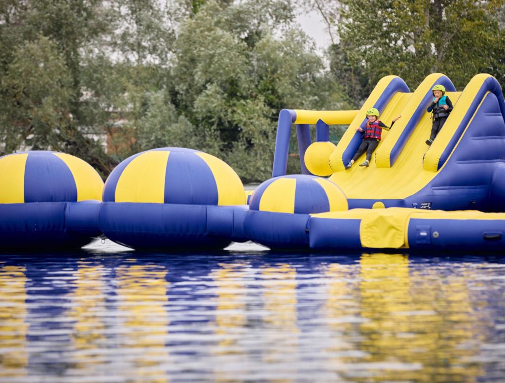 Children sliding into the water from the inflatable aqua park assault course at Billing Aquadrome.