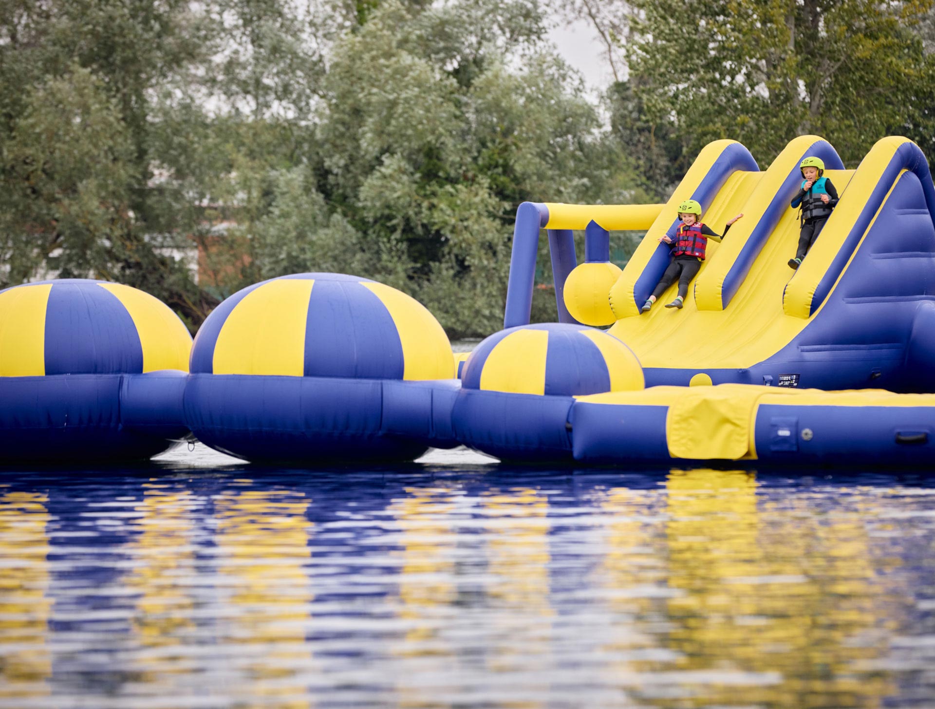 Children sliding into the water from the inflatable aqua park assault course at Billing Aquadrome.