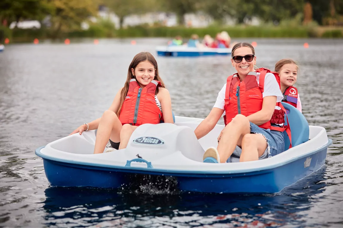 Family enjoying pedal boating together on the lake during outdoor activities at Billing Aquadrome