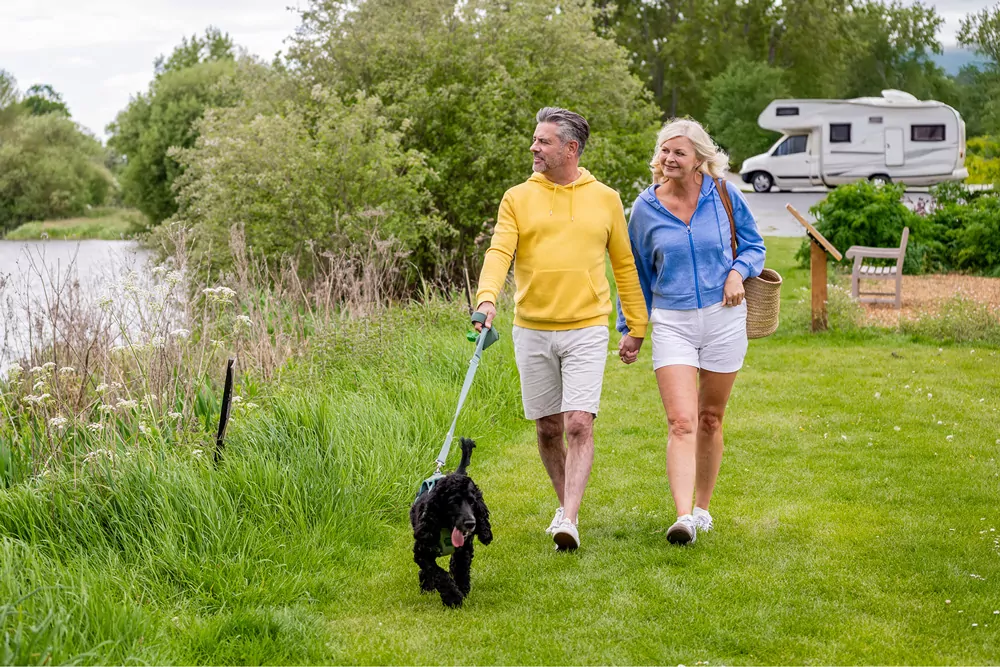 Couple walking their dog along a scenic park pathway near holiday accommodation at Billing Aquadrome