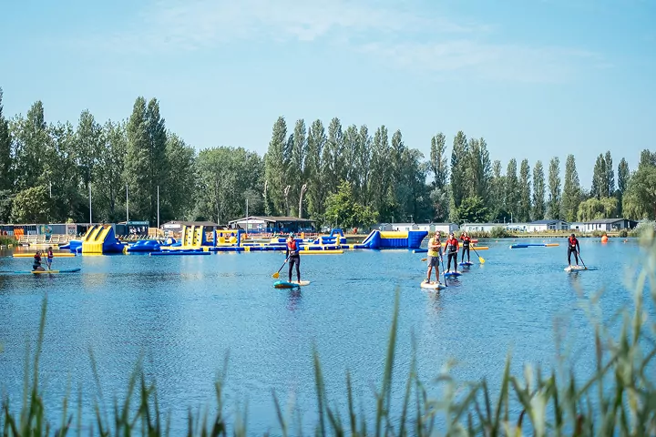 Group of people enjoying stand-up paddleboarding on a sunny day at the lake in Billing Aquadrome