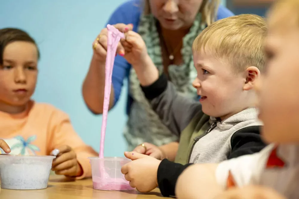 Children smiling and playing with homemade slime during a fun indoor slime-making activity at Billing Aquadrome.