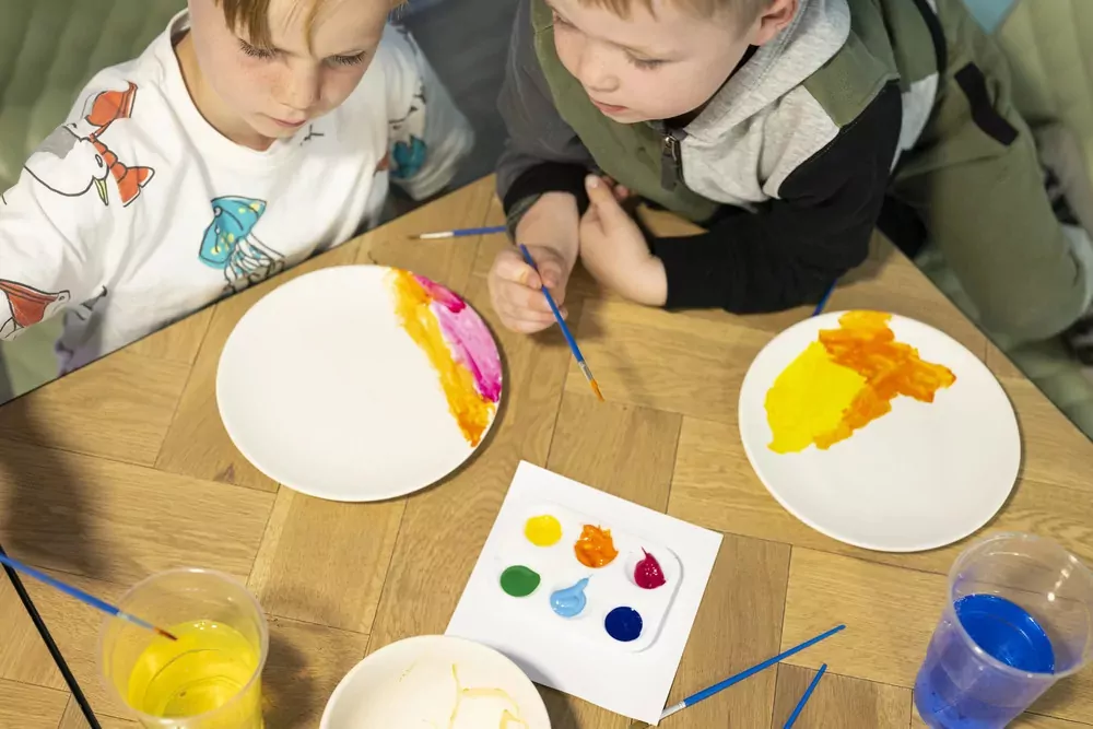 Children enjoying an indoor arts and crafts activity, painting colourful designs on plates at Billing Aquadrome.