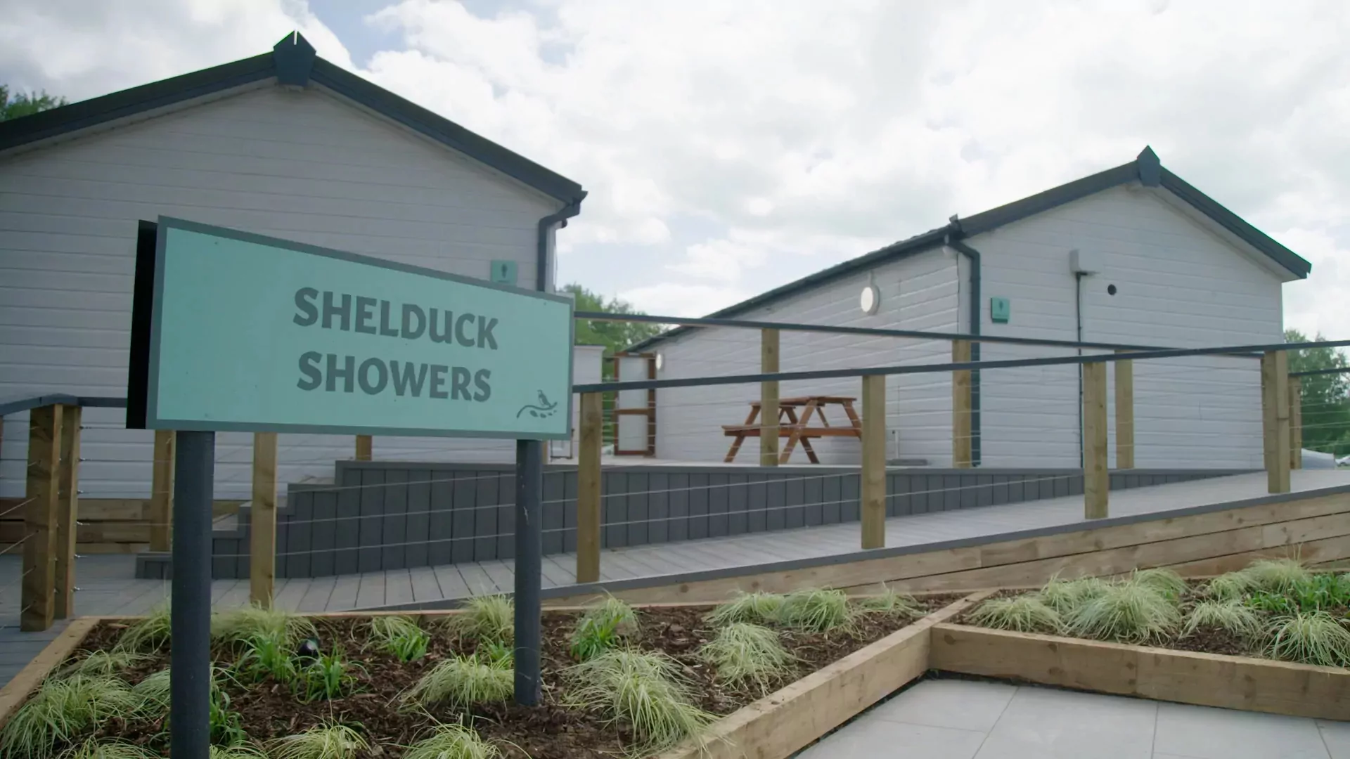Exterior view of the Shelduck Showers building with modern facilities and outdoor seating area at Billing Aquadrome.