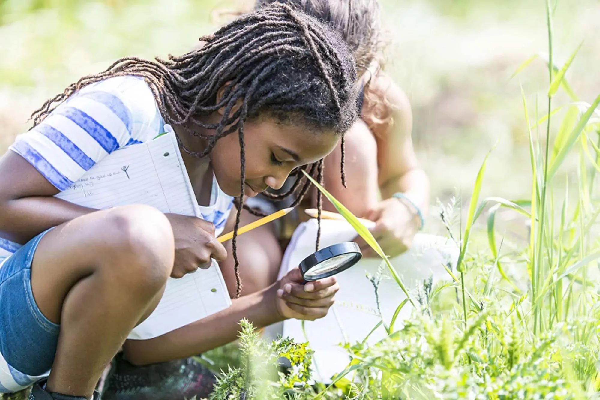 Children exploring plants with a magnifying glass during a nature discovery activity at Billing Aquadrome.