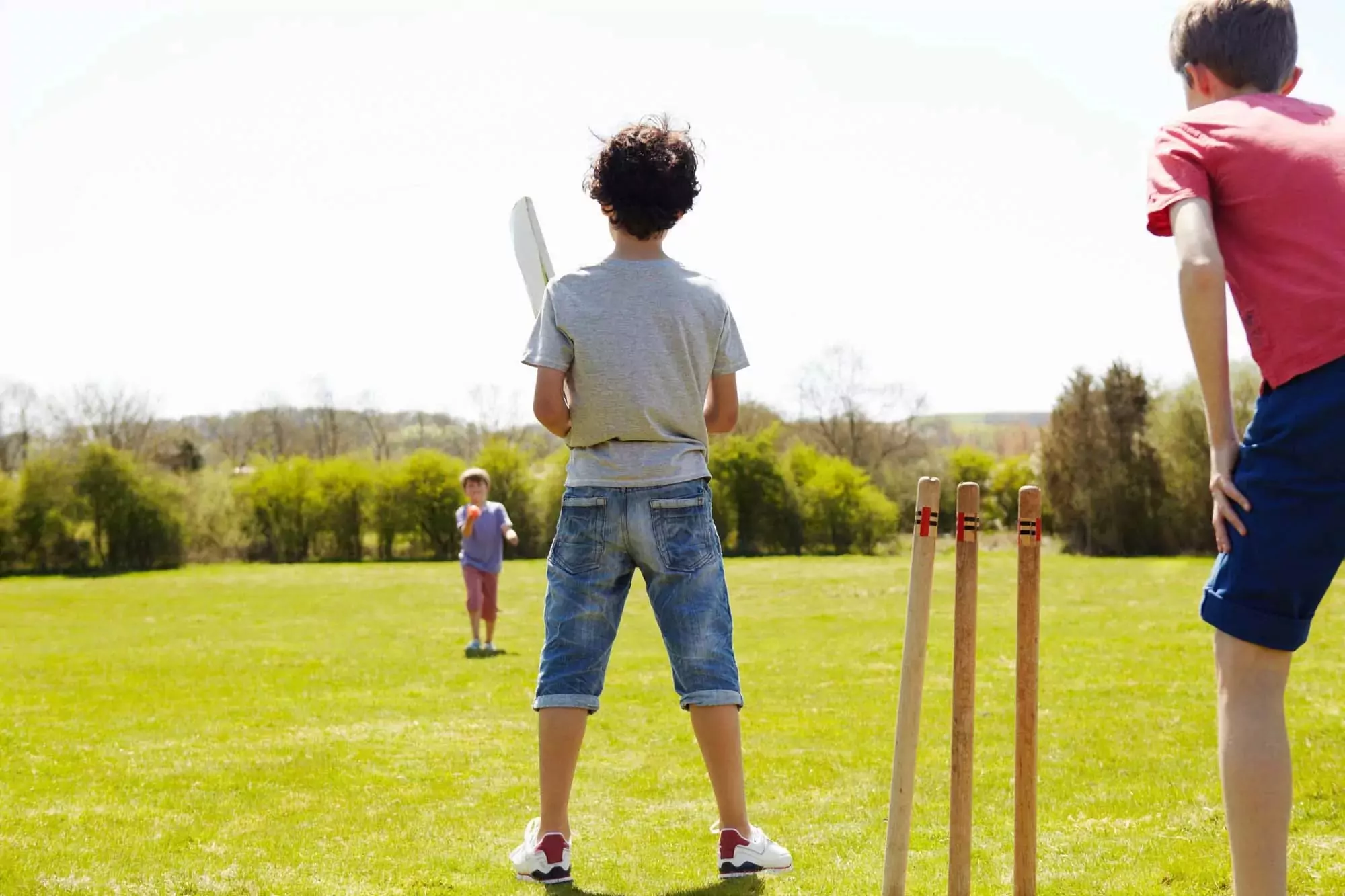 Children enjoying a game of cricket on the grass at Billing Aquadrome on a sunny day