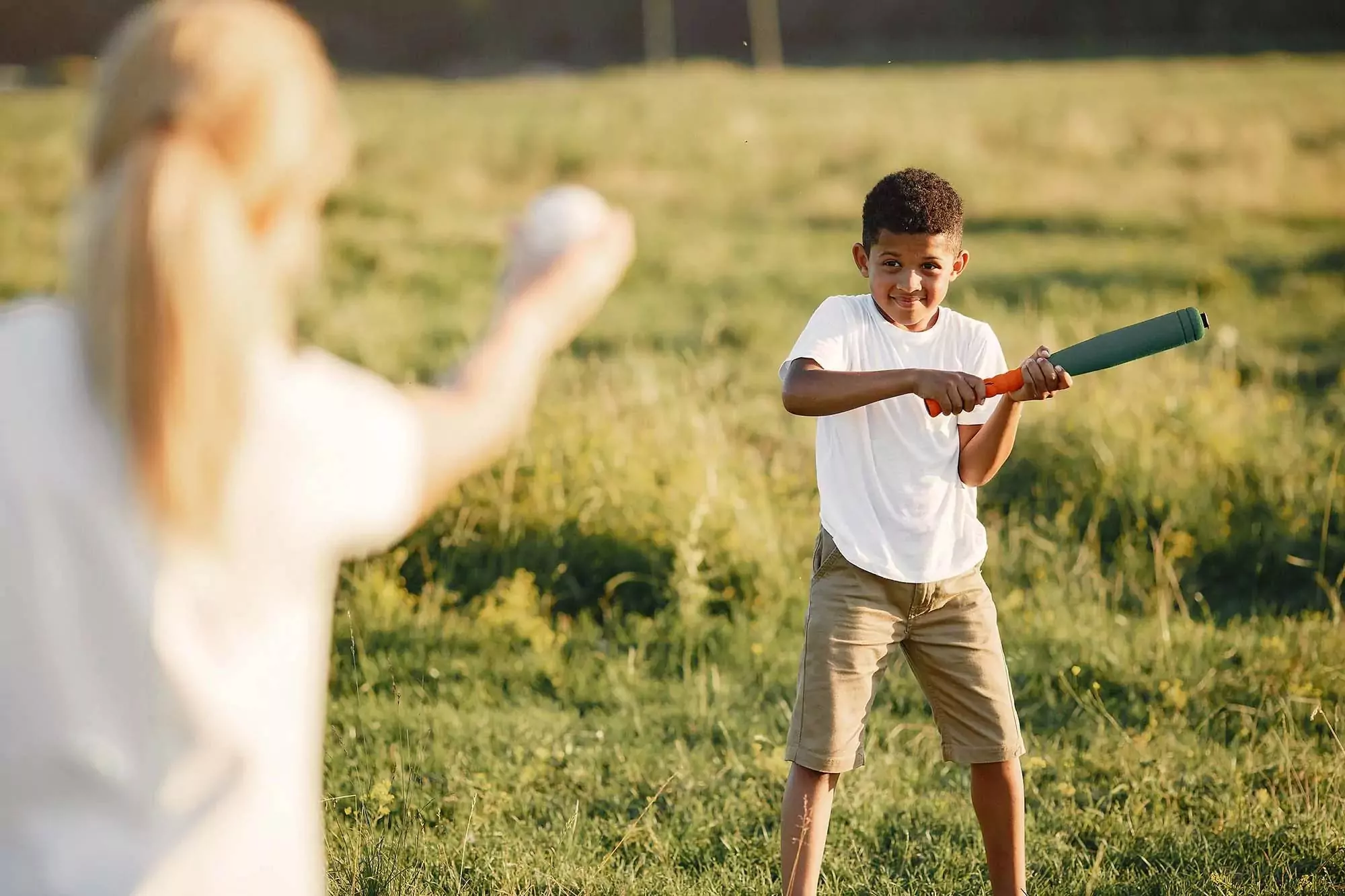 A young boy at Billing Aquadrome playing rounders in a sunny field.
