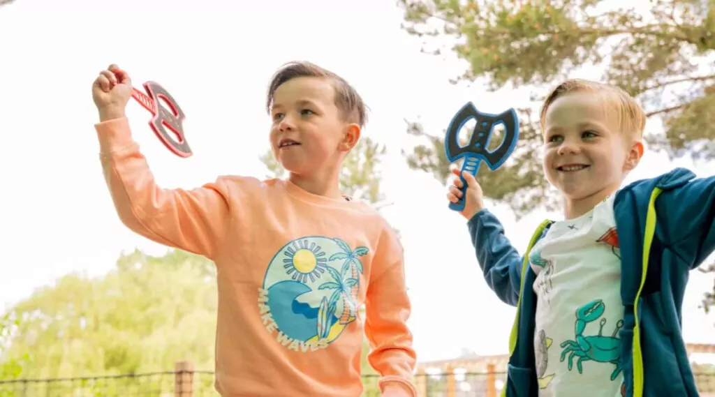 Two young boys smiling while playing a fun axe throwing game at Billing Aquadrome