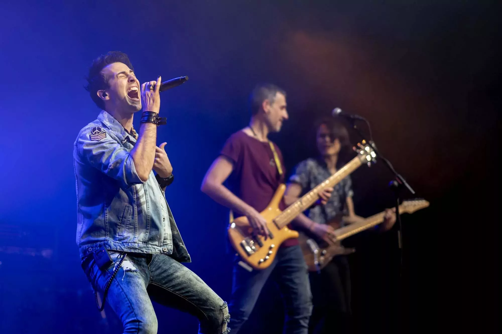 Lead singer passionately performing on stage with a rock band at Billing Aquadrome