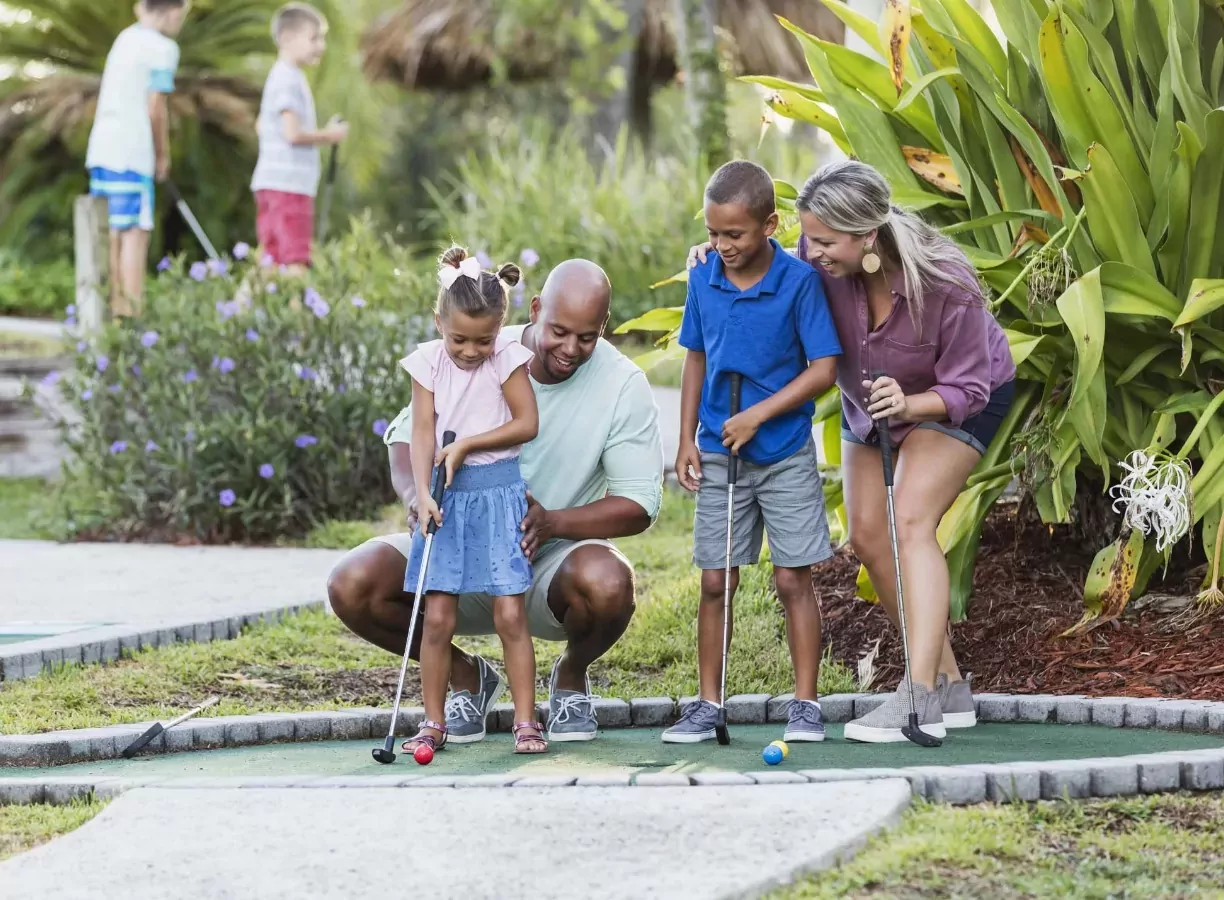 Family with two children playing mini golf together on a sunny day at Billing Aquadrome