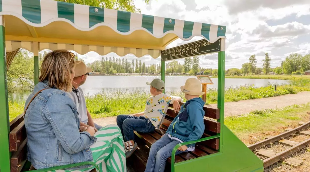 Family enjoying a scenic miniature train ride around the lake at Billing Aquadrome on a sunny day