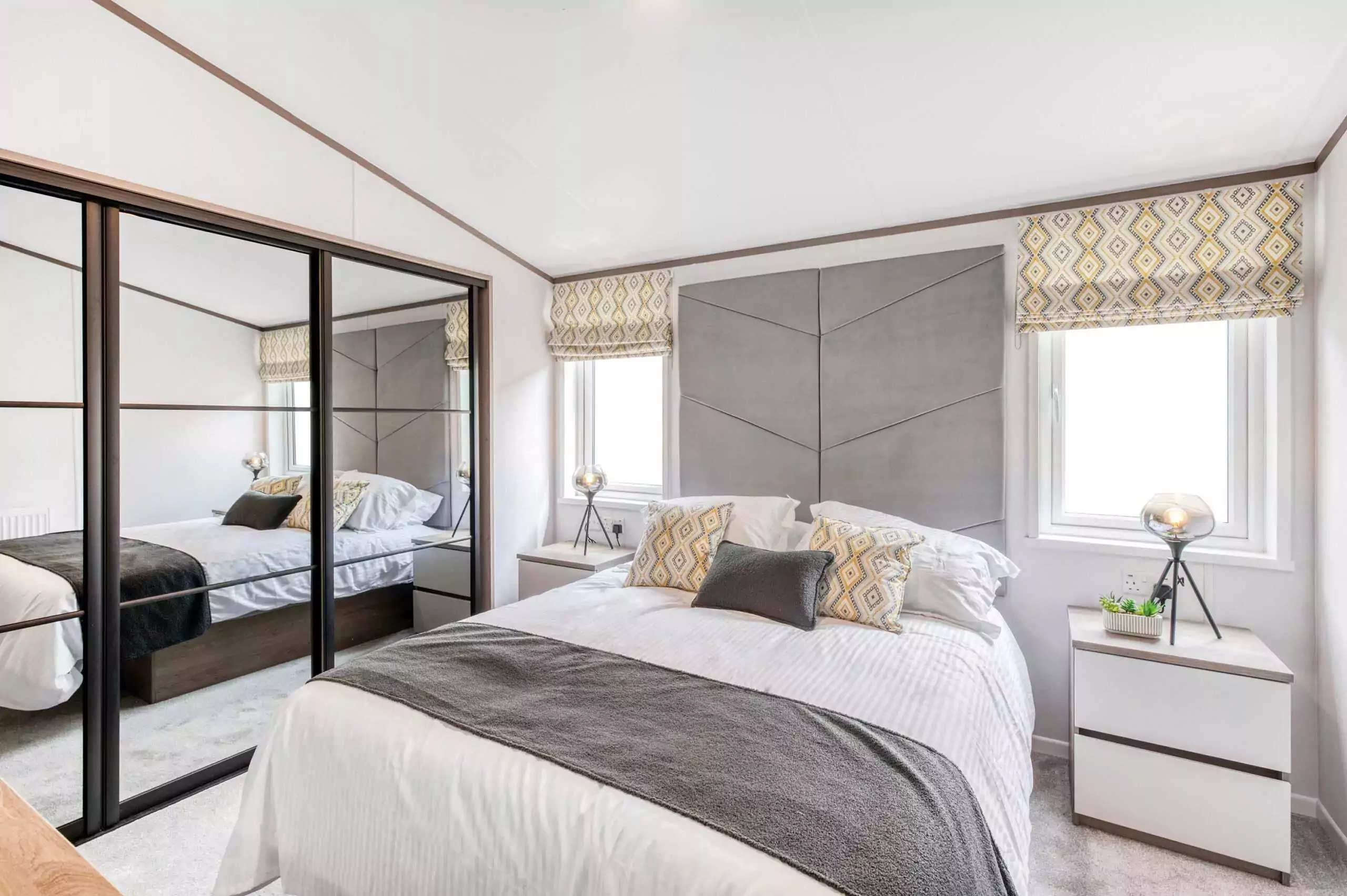 Bright and modern double bedroom inside a Meadow Bay Villages static caravan, featuring mirrored wardrobes, soft lighting, and stylish decor.