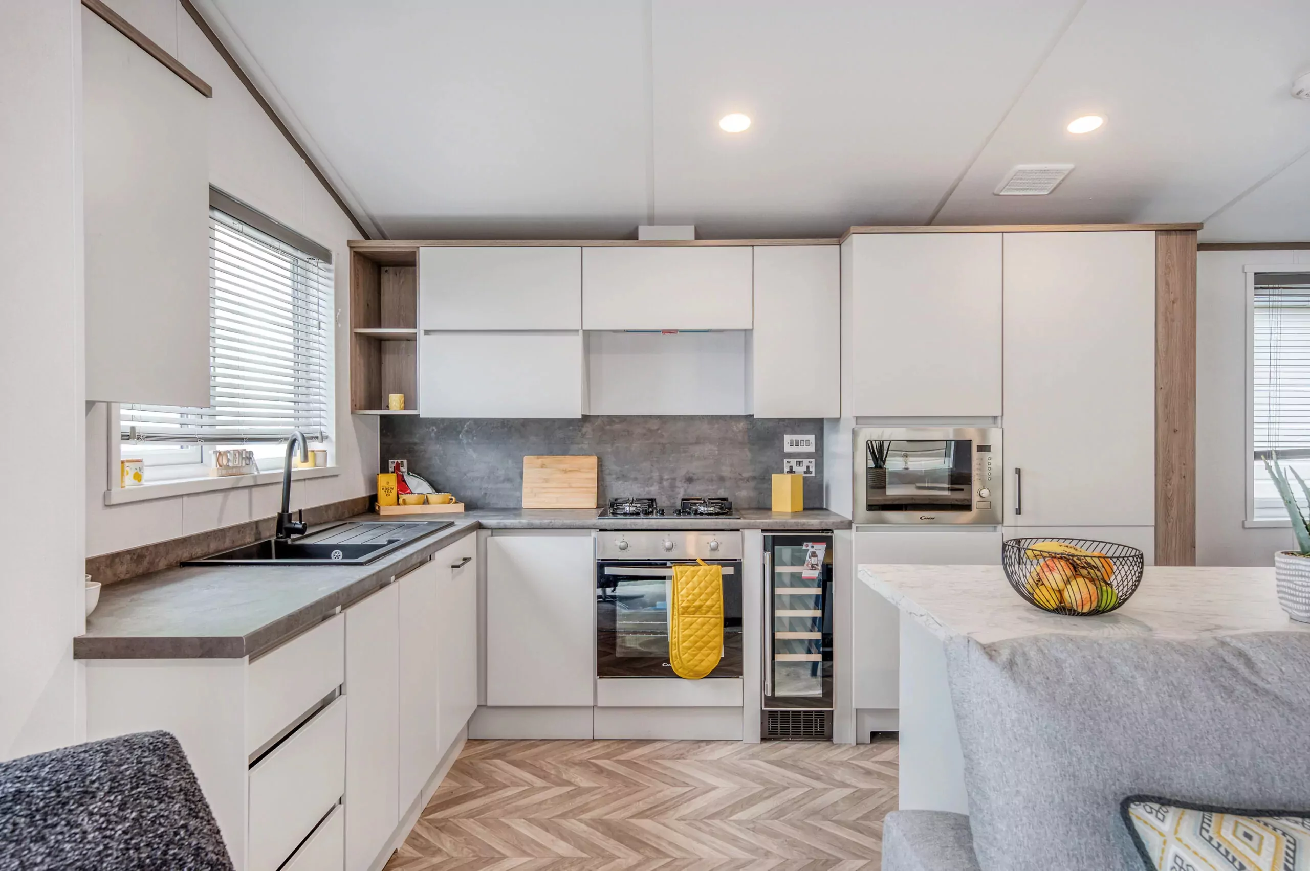 Contemporary kitchen inside a Meadow Bay Villages holiday caravan, featuring integrated appliances, breakfast bar, and modern storage layout.