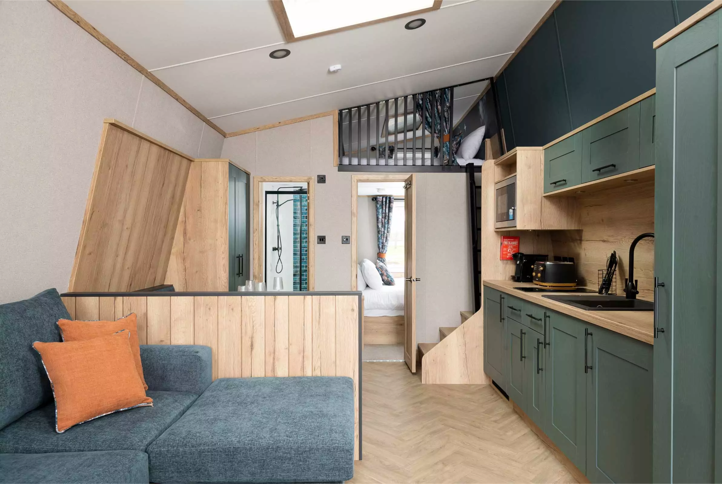 Contemporary glamping pod interior at Meadow Bay Villages’ Billing Aquadrome, featuring compact kitchen, lounge area, shower room, and elevated sleeping space