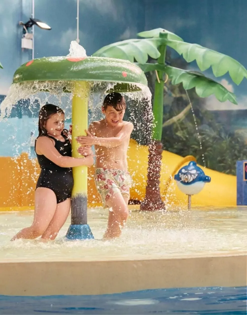 Children playing under a water feature in the indoor swimming pool at Billing Aquadrome.